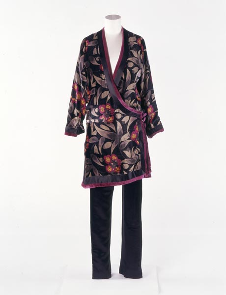 Woman's pyjama suit, made up of  loose black bottoms and an Oriental-looking long black top with purple trim. This is decorated with foliage and flowers.