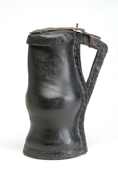 Black shiny leather jug with a lid attached to the handle with a metal hinge. On the base and the right-hand side of the jug the leather is sewn together with a double row of stitching.