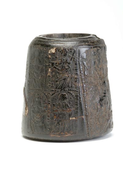 Black inkwell, made from horn. The horn has been pressed so its surface is decorated with tiny figures of saints.