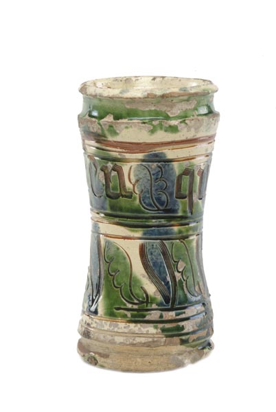 Small cream-coloured jar with green and blue glaze and a design of leaves, lines and letters scratched through the cream surface, revealing the red clay underneath.