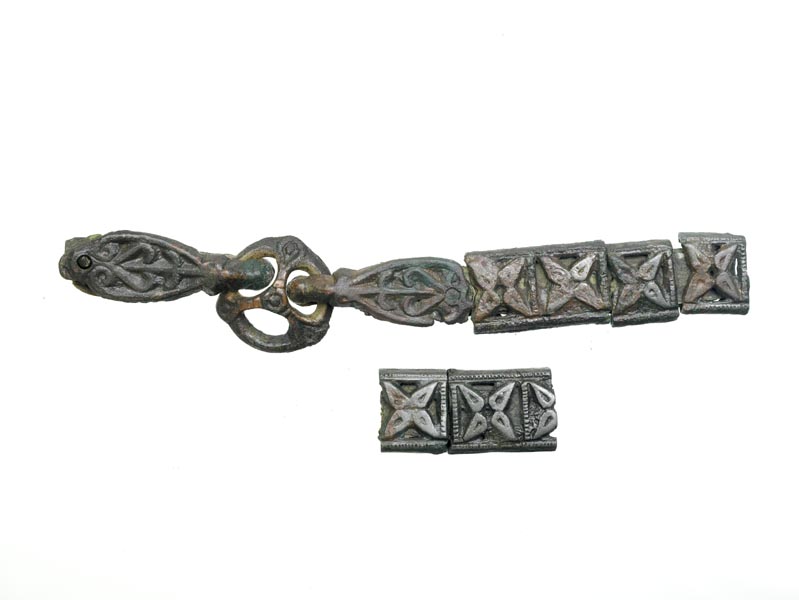 Part of a Viking sword belt. The leather can just be seen underneath decorative metal mounts. The belt has a link with 3 loops towards the left-hand end.