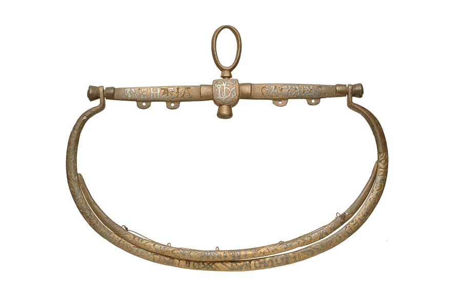 Copper alloy purse frame, made from a straight bar across the top with 2 curved frames hanging from it. It has an inlaid inscription. There is a large loop at the top to attach the purse to a belt.