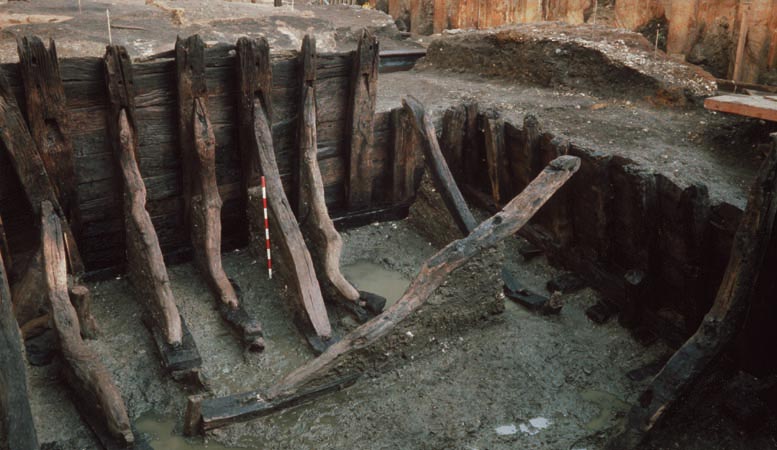 Photograph of the archaeology excavation of the Billingsgate revetment. It resembles a very large, wooden fence with thick supporting struts and beams to brace it.