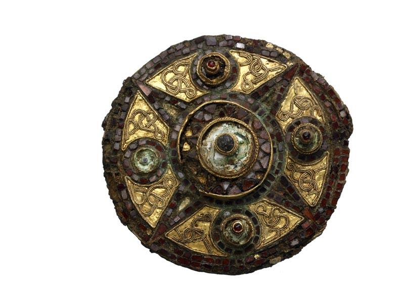 Circular brooch, decorated with gold and tiny, square garnets. The garnets form a ring around the edge and a 4-pointed star in the centre.