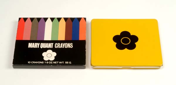A metal box containing make-up crayons. Next to it the box's paper cover labelled 'Mary Quant Crayons'