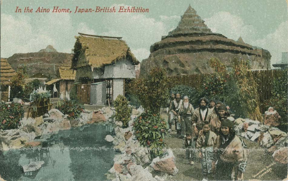 Image of group of people standing by a pool with thatched houses and taller structures in the background.